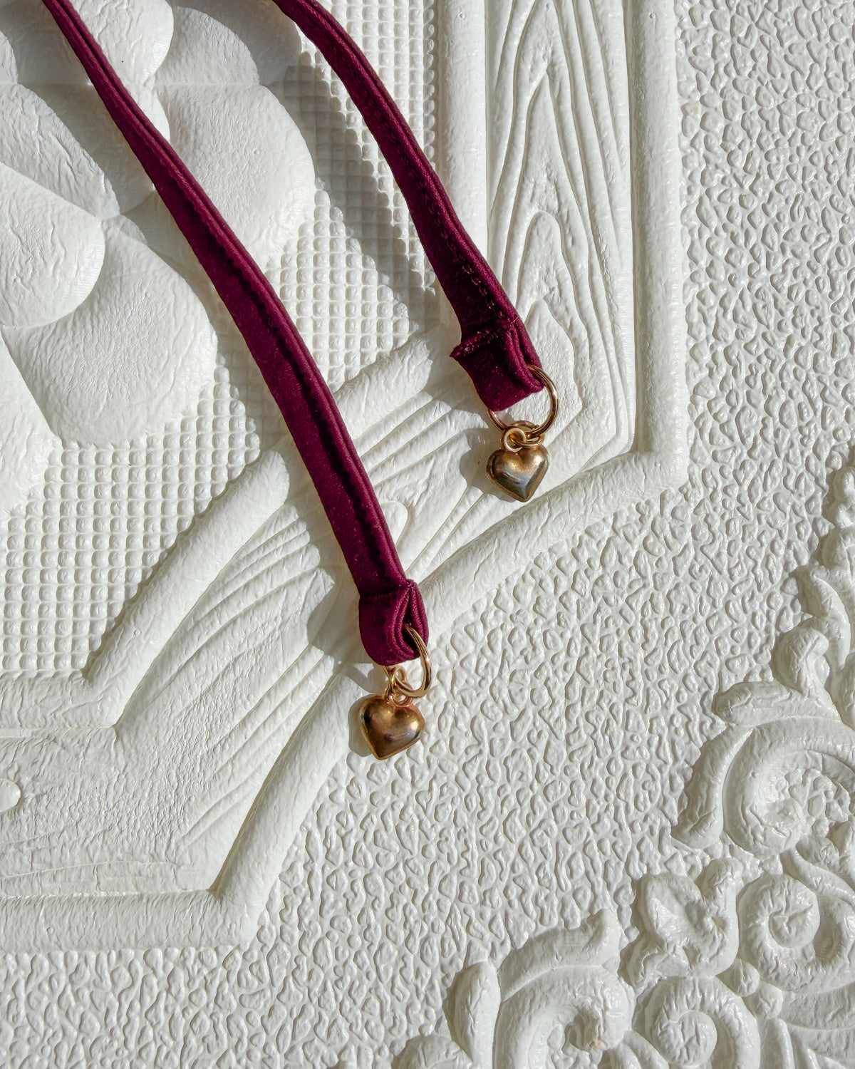 Close-up of the Crimson Evangeline Bikini straps with gold heart charms.